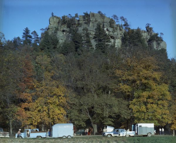 Men and women with horse trailers gather beneath Castle Rock. The group gathered there for a western-style horseback riding meet.