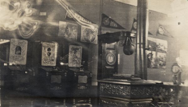 A night photograph of 'obscene' slot-machines in a penny arcade. On display are pennants on the wall, including "Iowa" and "Nebraska." Another machine holds a punching bag.