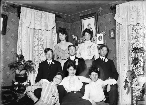 Group of five young women and three young men posing for a portrait in a home.
