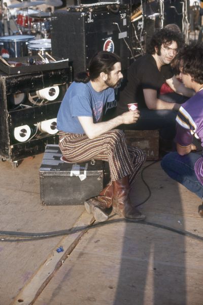 Grateful Dead guitarist Jerry Garcia (seated, middle) with drummers Bill Kreutzmann and Mickey Hart, sit on the Sound Storm stage before playing.