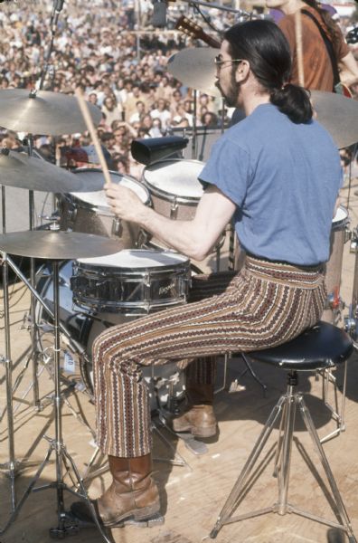 Mickey Hart, drummer for the Grateful Dead, performing with the band on stage at the Sound Storm music festival. Guitarist Bob Weir is visible on the right, and in the background is a large crowd.