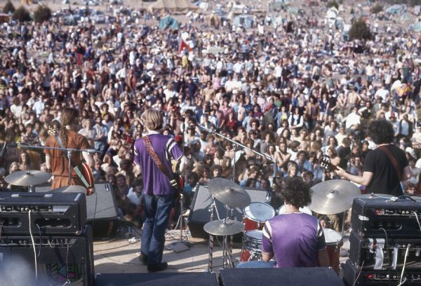 View from back of stage of the Grateful Dead, featuring Bob Weir, Phil Lesh, Bill Kreutzmann, and Jerry Garcia, playing on stage at the Sound Storm Festival with the audience in the background.