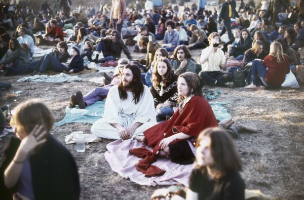 A group of audience members sit on blankets at the Sound Storm festival with a large crowd visible behind them.