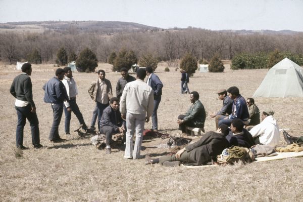 A crowd of African-American men standing and sitting in the camping area of the Sound Storm music festival before most of the audience arrives.