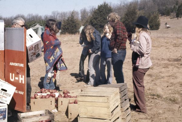 A group of people eat and help unload crates of apples from a U-Haul trailer in the campground area of the Sound Storm music festival during the construction of the food stalls.