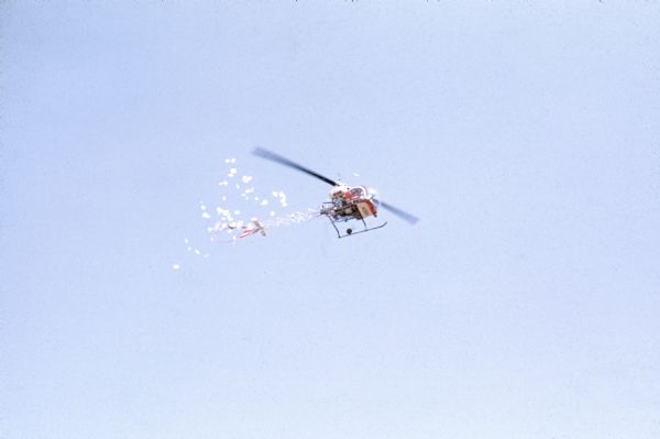 A helicopter drops papers onto the audience at the Sound Storm music festival. It was widely rumored that Ken Kesey was at the festival and that he dropped tabs of acid on the audience, but in reality the helicopter dropped fliers made by festival staff identifying narcotics officers or undercover police who had infiltrated the event.