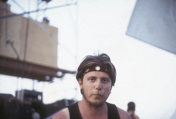 Robert Pulling wearing a headband in a self-portrait. He was a photographer for the Sound Storm music festival. A festival staff member is visible in the background.