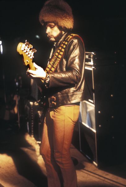 Keith Anderson, bass player for Illinois Speed Press, wearing a furry hat and a leather jacket while playing on stage at night at the Sound Storm music festival.