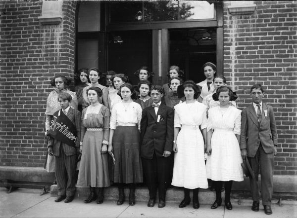 Group of children pose in front of the entrance to a brick building.
First row, reading from left to right: Willie Wieland, Millie Geyer, Florence, Wieland, Lee Neises, Vera Burr, Kathryn Burr, Douglas Hampton.
Second row: Christine Waltz, Anna Jones, Ethel Hamilton, Susie Walz, Rosie Wiest, Rosa Bendorf.
Third row: Pearl Curtis, Ethel Groom, Helen Pendleton, Hilda Vosberg, Lenice Carns.