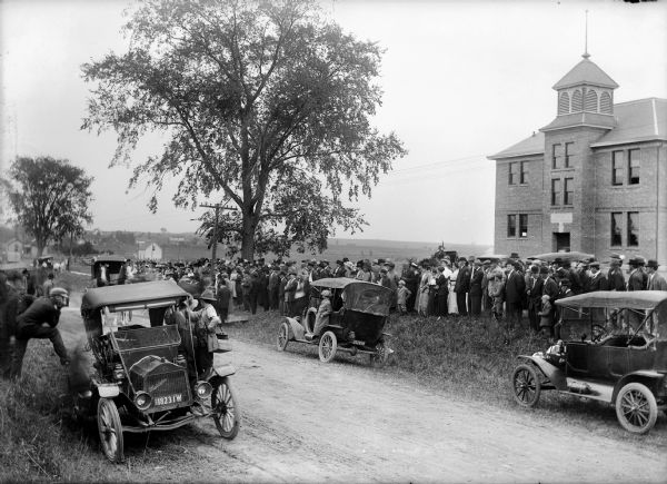 View from across the road of a large group of people on the front lawn of the Union High School during the second annual fair.
