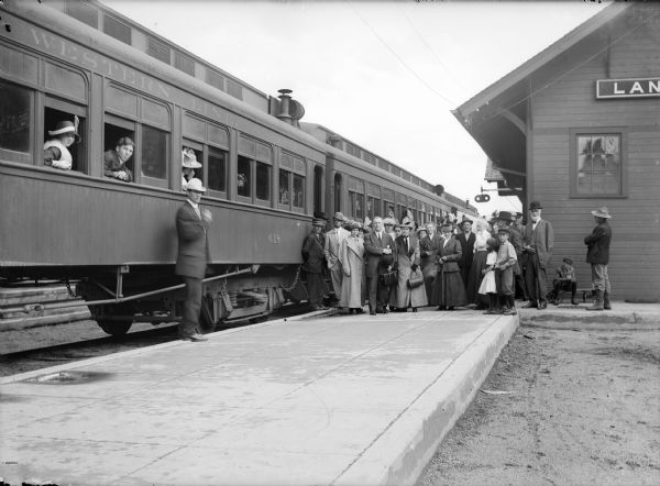 Group of people posing for photograph at train station next to train.