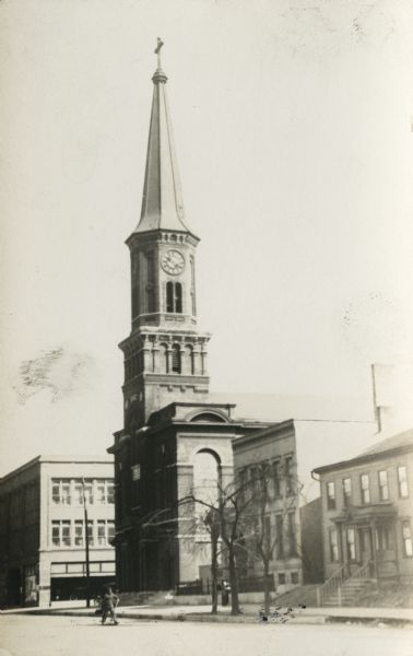 View looking northeast of St. Mary's Catholic church at the  
southeast corner of East Kilbourn Avenue and North Broadway. 
A man is walking across the street.
