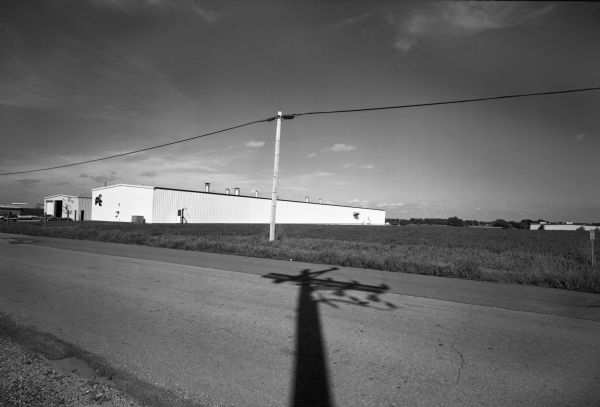 A large telephone pole shadow is cast over a road in the industrial park on Evergreen Road.