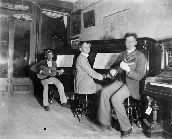 Three Men Playing Musical Instruments, Edward Schwaller at left; Frank H. Schwaller in middle; man at right unidentified.  Probably inside Schwaller Music Store on Pine Street.
