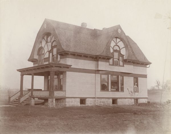 Exterior view of the Leslie Bird house. Bird worked as the Registrar at the University of Wisconsin-Madison. The two-story house is built on a stone foundation. Additionally, the house has a front porch, decorative dental work, windows, siding and a steep, curved roof.