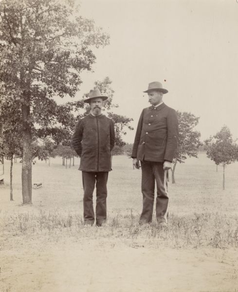 Two military officers, Major Mahoney and H. Schildhauer stand, in a field with small saplings.