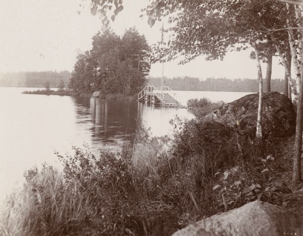View of a rural lake with a footbridge leading to a small island.