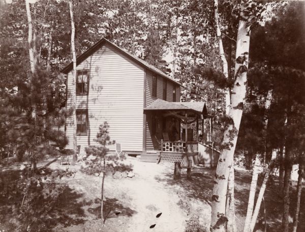 Exterior view of U.S. Marshall Canon's summer cottage. The two-story cottage has an outdoor porch and is surrounded by trees.