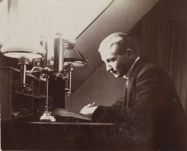 Mr. Edward Schildhauer sitting at a desk and writing in a book.