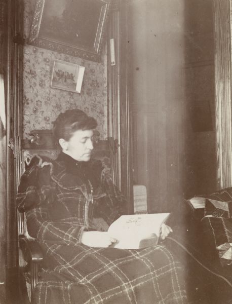 Mrs. Annie Schildhauer sitting indoors reading a book.