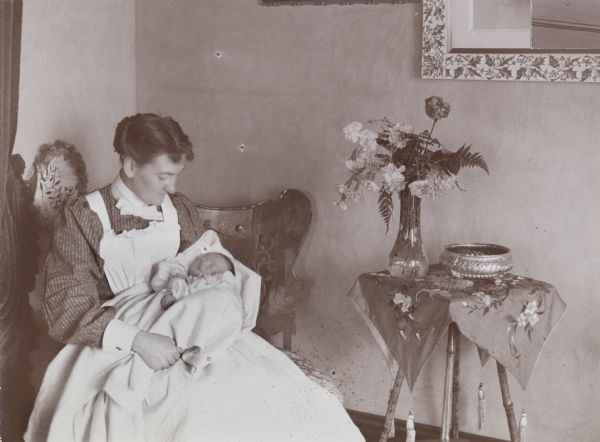 A nurse sits with Mrs. D.W. Osborn's week-old newborn.