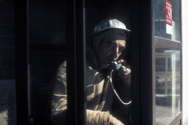 Construction worker talking in a telephone booth.