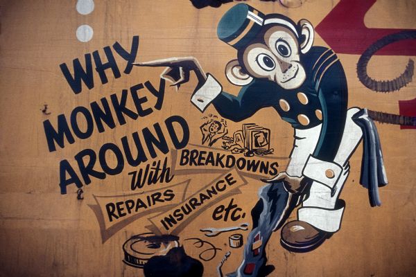 Close-up of an advertisement that reads, "Why Monkey Around with breakdowns, repairs, insurance, etc." There is a cartoon monkey pointing to the dialogue along with various mechanical tools.
