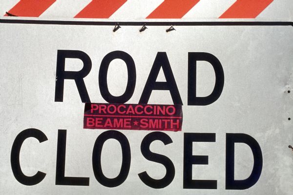 View of a "Road Closed" sign with a sticker on it that reads, "Procaccino / Beame * Smith."