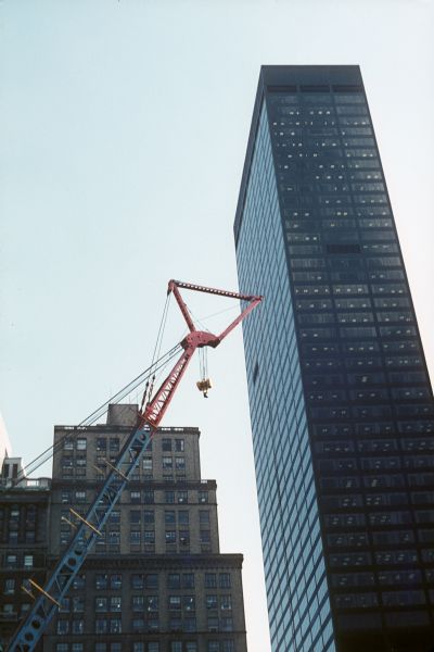 View of the top of a crane at the World Trade Center construction site. In the background is a skyscraper.