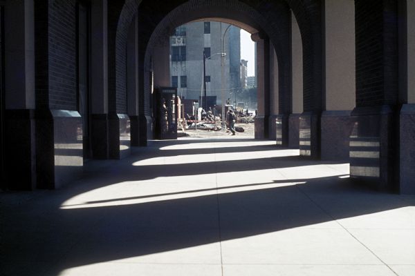 View of construction site through arches casting shadows.