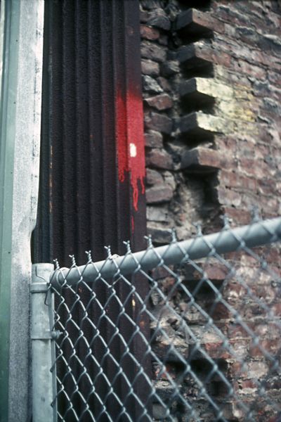 Close-up of a chain-link fence near a deteriorated brick wall.