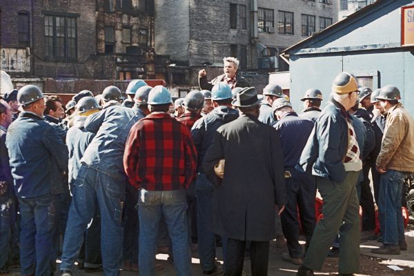 A group of construction workers gather to listen to a speaker near the office for the Sand Chapter of Mechanical Contractors at the construction site for the World Trade Center.
