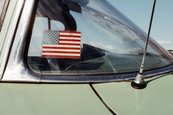 An American flag sticker is visible in a back window of an automobile.