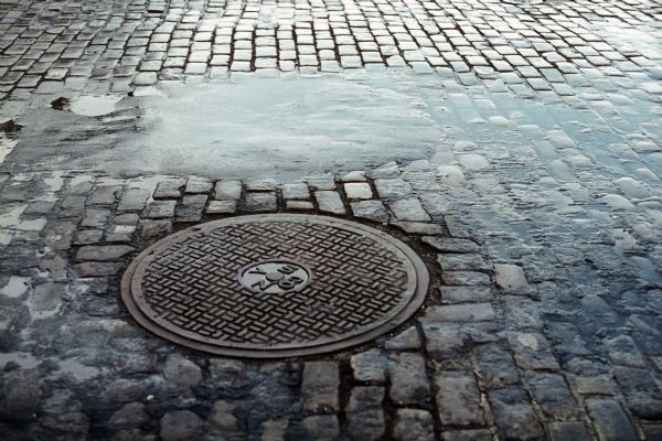View of a manhole cover on a cobblestone street.