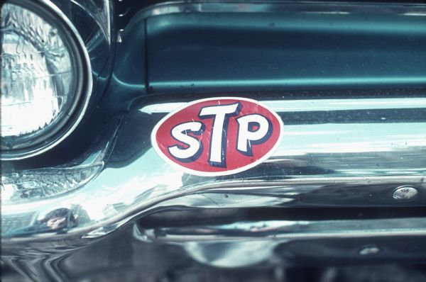 STP, Scientifically Treated Petroleum, a fuel additive, is advertised on a fender of an automobile.