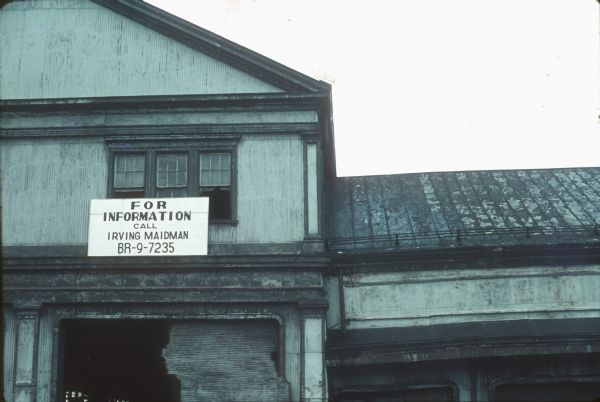 A sign on the exterior of a deteriorated building that reads: "For Information Call Irving Maidman BR-9-7235," near the World Trade Center construction site.