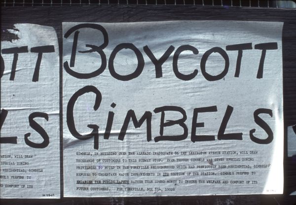 Sign on street is protesting the Gimbels department store. Underneath the large text, it reads, "Gimbels, in building over the already inadequate 86 IRT Lexington Avenue Station, will draw thousands of customers to this subway stop. Even though Gimbels was given special zoning priveledges to build in the Yorkville neighborhood which had previously been residential, Gimbels refuses to undertake major improvements in its section of the station. Gimbels prefers to endanger the public safety rather than spend money to insure the welfare and comfort of its future customers. For Yorkville, Box 534, 10028."