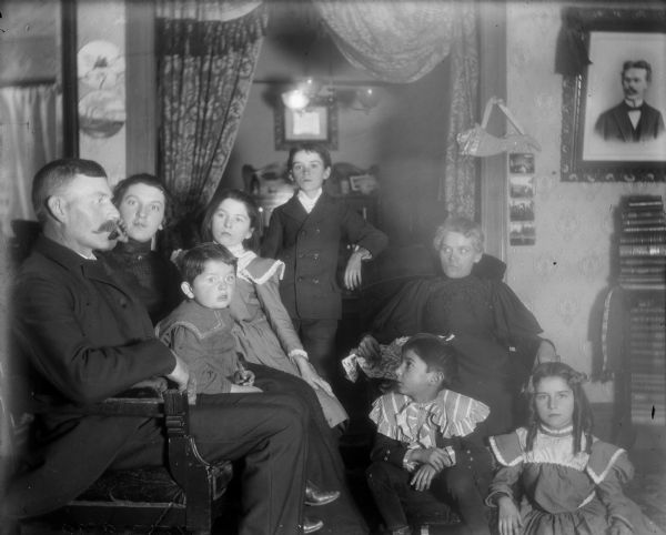 A large group of relatives, including men, women and children, are gathered together indoors.