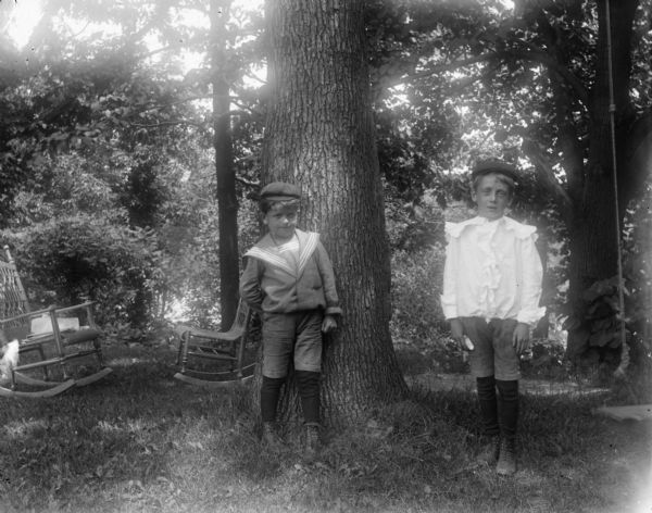 Syl and Harold pose in front of a tree. There are two chairs on the left, and a wooden swing hangs from the tree to the right.