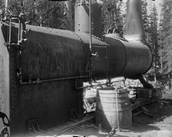 A large upright boiler functioning as part of the Leighton-Wyoming mining camp.