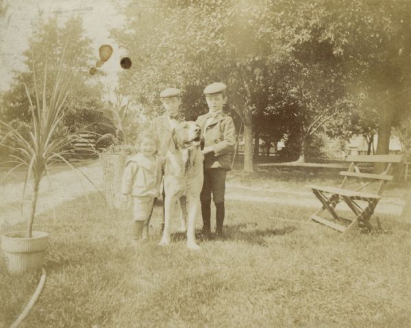 Syl, aged two, with a St. Bernard dog in the backyard of the home of the Esau's, with Earl and Walter Esau.