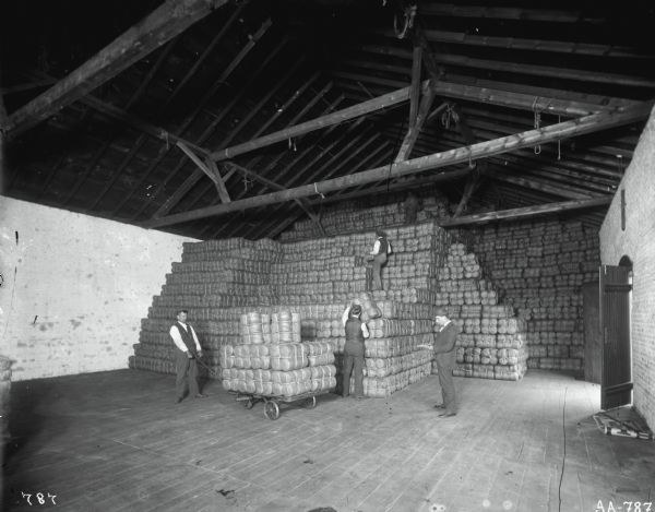 Workers stacking bundles of McCormick binder twine in a warehouse, possibly at the McCormick Twine Mill.