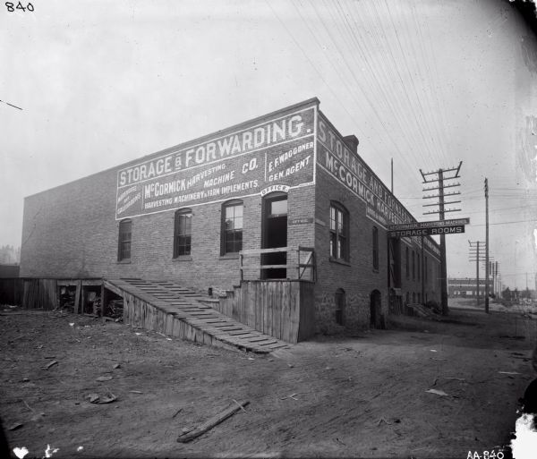 Exterior view of dealership building of E.F. Waggoner, general agent for the McCormick Harvesting Machine Company. Text on the side of the building reads: "Warehouse and Salesrooms," and "Storage & Forwarding." The Union Warehouse and Machine Company building is in the background.
