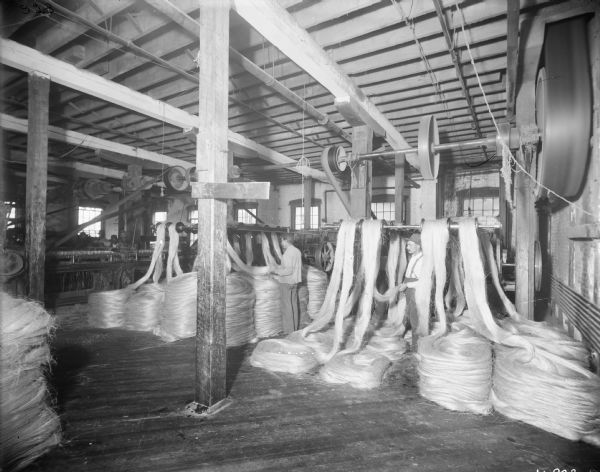 Factory workers feeding sisal or manila fiber into machines, most likely at the McCormick Twine Mill.
