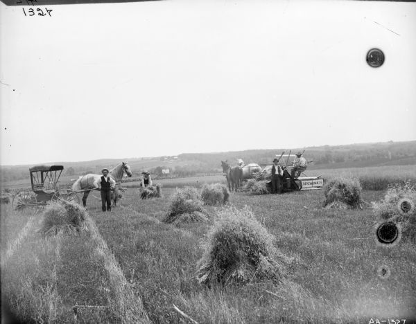Men with a horse-drawn McCormick grain binder and horse-drawn carriage in a field.