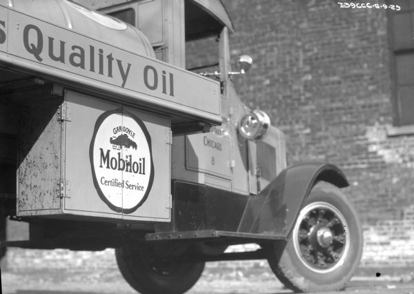Low angle close-up of the front side of an International oil delivery truck. The side of the truck reads "Quality Oil" and below is a logo reading "Gargoyle Mobiloil Certified Service." The cab door reads: "Chicago 8."