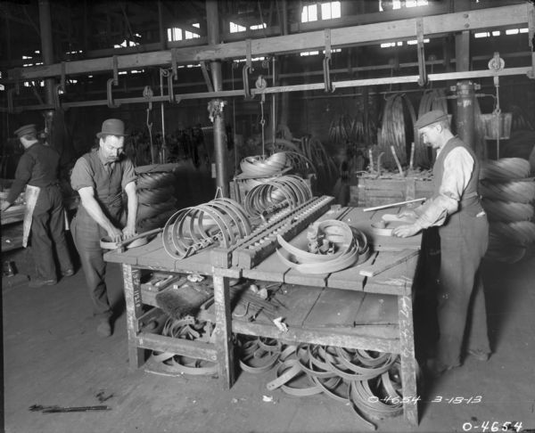 Factory workers testing newly manufactured harrow spring teeth at International Harvester's Osborne Works. The factory was owned by the D.M. Osborne Company until 1903, when it was purchased by International Harvester. The factory was later known within the company as the "Auburn Works." It was located at 5 Pulaski Street.