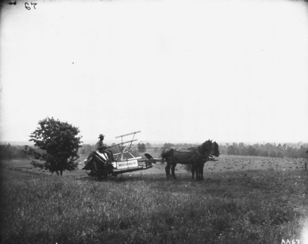 Right side profile view of a man sitting on horse-drawn McCormick binder on a transport truck in a field.