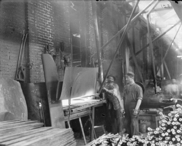 Men working at what appears to be a forge in the foundry area of McCormick Works. A pile of materials is in the foreground.