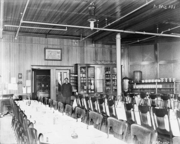 Interior view of the dining room in the McCormick Works Club House. A waiter stands near the door to the kitchen in the background.